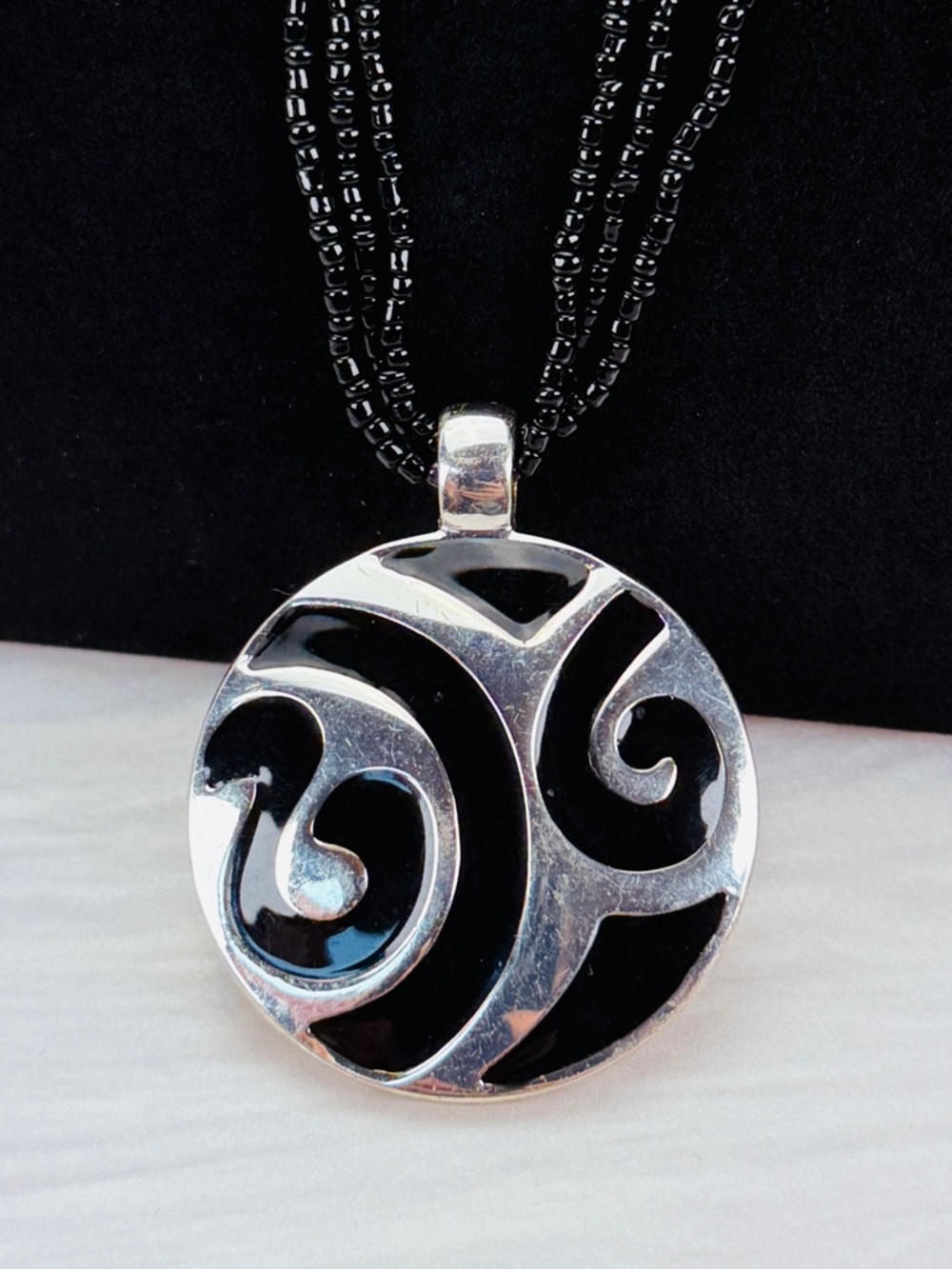 Black and silvertone pendant beaded three strand necklace